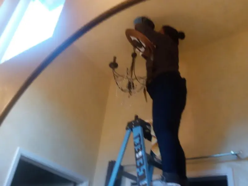 Electrician installing a chandelier in a Lynn residence